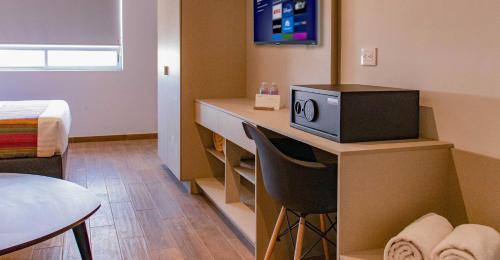 a room with a desk with a television on it at Estancias VIVE MX el marqués in Hércules