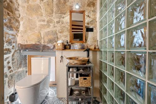 a bathroom with a toilet and a stone wall at Lo Raconet d'Arnes in Arnés