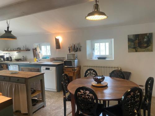 une cuisine avec une table en bois et une table et des chaises dans l'établissement La Bastide des Chênes Lacoste, à Lacoste