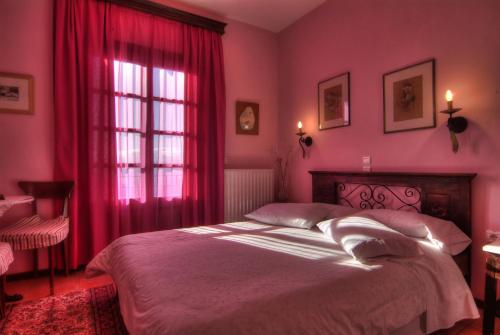 a bedroom with a bed with pink walls and a window at Nefeles in Arachova