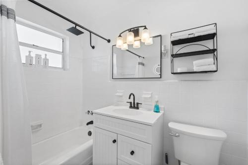 a white bathroom with a sink and a toilet and a tub at Nestled in North Port in North Port