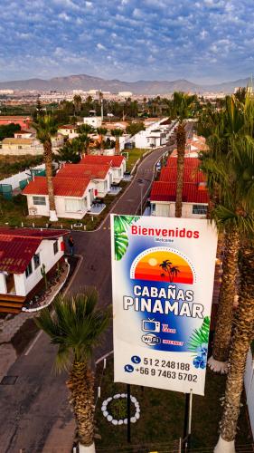 a sign in the middle of a town with palm trees at Cabañas Pinamar in La Serena
