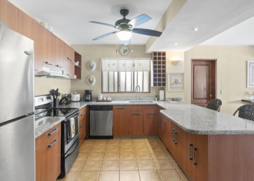 a large kitchen with wooden cabinets and a ceiling fan at Bahia Pez Vela Resort in Ocotal