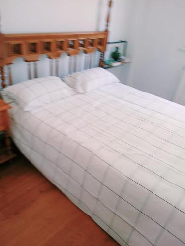 a bed with a white comforter in a room at pension Tolima in Cabezón de la Sal