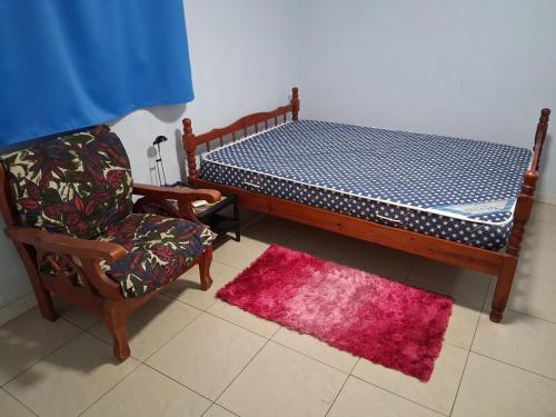 ein Schlafzimmer mit einem Bett, einem Stuhl und einem Teppich in der Unterkunft Écrin de Jasmin in La Trinité