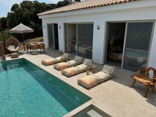 a swimming pool with pillows next to a house at XTC Villas Kefalonia - Villa X in Argostoli