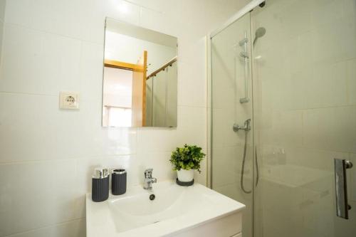 a white bathroom with a sink and a shower at Estúdio Kubata Hill in Parede