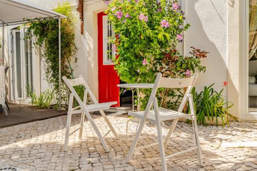 two chairs and a table in front of a red door at Lisbon Garden Stays, Apt close to Tram 28, Views & São Jorge Castle in Lisbon