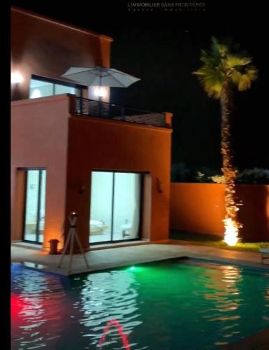 a house and a swimming pool at night at VILLA NOÛR PALACE avec piscine jaccuzi à Marrakech in Marrakech