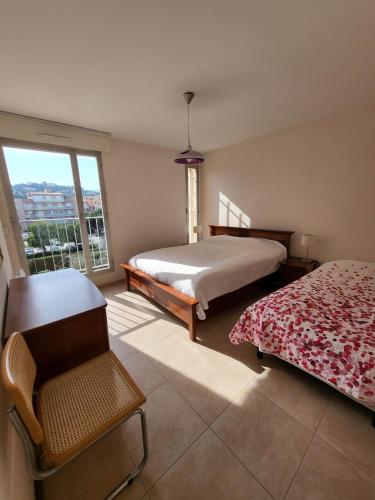 une chambre avec un lit, une chaise et une fenêtre dans l'établissement Superbe Appartement T3 vue mer en centre ville à 5 minutes à pied de la place, à Cavalaire-sur-Mer