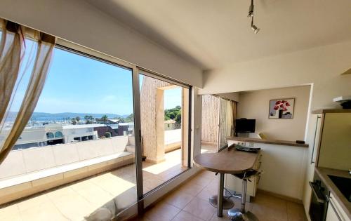 une pièce avec un bureau et une grande fenêtre avec vue dans l'établissement Superbe Appartement T3 vue mer en centre ville à 5 minutes à pied de la plage, à Cavalaire-sur-Mer