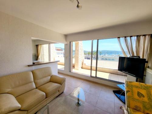 un salon avec un canapé et une grande fenêtre dans l'établissement Superbe Appartement T3 vue mer en centre ville à 5 minutes à pied de la plage, à Cavalaire-sur-Mer