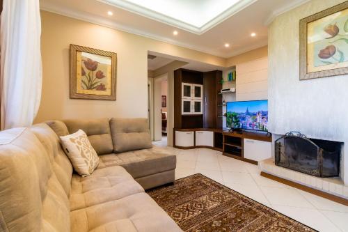 a living room with a couch and a flat screen tv at Rosa Edificio Jardim dos Lagos in Canela