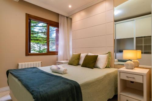 a bedroom with a large bed and a window at Rosa Edificio Jardim dos Lagos in Canela