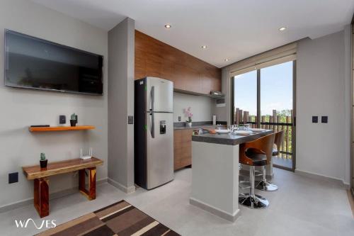 a kitchen with a stainless steel refrigerator and a counter at 1 bedroom with park view in condominium with gym sauna and steam room in Tulum