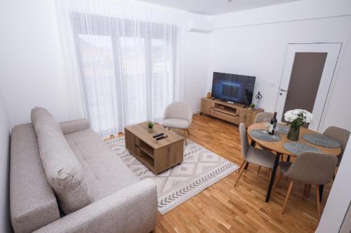 a living room with a couch and a table and a tv at Central Rooftop Apartment in Trebinje