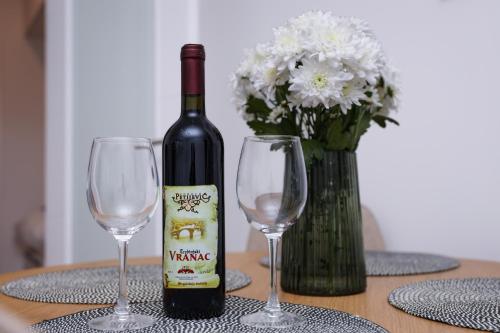 a bottle of wine sitting on a table with two wine glasses at Central Rooftop Apartment in Trebinje