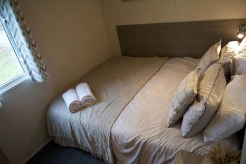 a bedroom with a bed with two towels on it at Cosy cabin for 6 in Great Billing in Great Billing