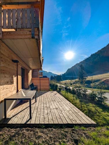 a wooden deck with a table on the side of a building at Spacieux appartement Morgins cheminée, terrasse et jardin in Morgins