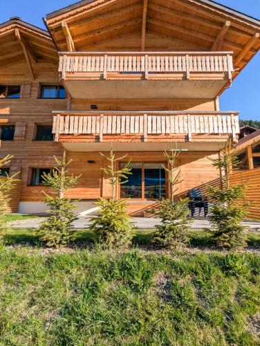 a wooden house with a balcony and trees in front of it at Spacieux appartement Morgins cheminée, terrasse et jardin in Morgins