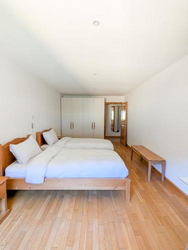 a bedroom with a large bed and a wooden floor at Spacieux appartement Morgins cheminée, terrasse et jardin in Morgins