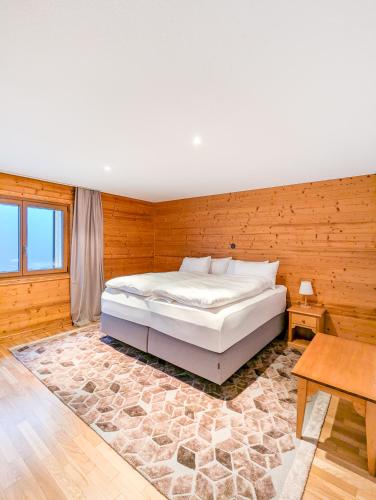 a bedroom with a bed and a wooden wall at Spacieux appartement Morgins cheminée, terrasse et jardin in Morgins