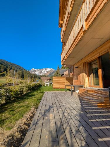 a wooden deck on the side of a house at Spacieux appartement Morgins cheminée, terrasse et jardin in Morgins