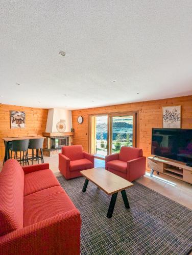 a living room with red furniture and a flat screen tv at Spacieux appartement Morgins cheminée, terrasse et jardin in Morgins