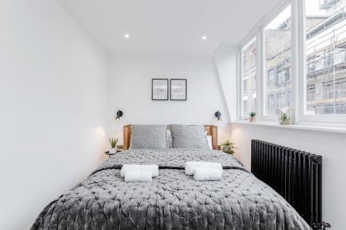 a bedroom with a large bed with two pillows at 2Bed 2Bath Apartment in Liverpool Street, Steps to Brick Lane, Spitalfields & Shoreditch in London