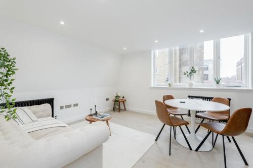 a white living room with a white couch and a table at 2Bed 2Bath Apartment in Liverpool Street, Steps to Brick Lane, Spitalfields & Shoreditch in London