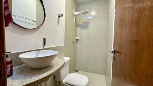 a bathroom with a sink and a toilet and a mirror at Flat Guarapari Praia das Castanheiras e Areia in Guarapari