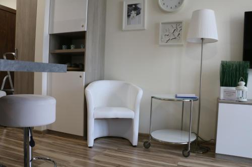 a living room with a white chair and a lamp at Apartament Przy Plaży in Krynica Morska