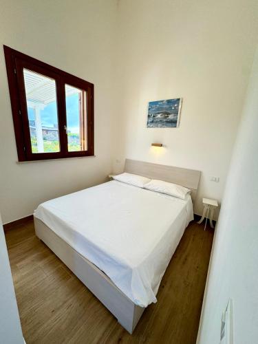 a bedroom with a white bed and a window at Aria case vacanze in Favignana