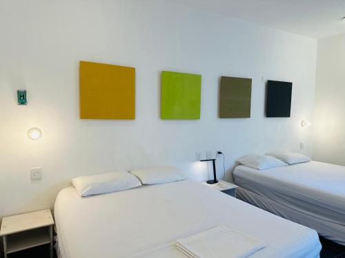 two beds in a room with paintings on the wall at Freelance Hostel in Tulum