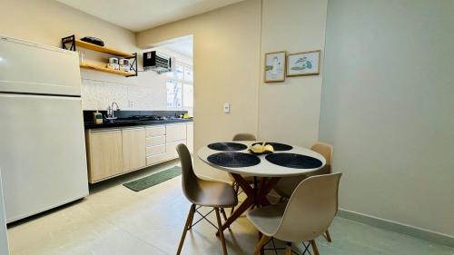 una cucina con tavolo, sedie e frigorifero di Quadra do Mar 2 Quartos Suite Praia do Morro Guarapari a Guarapari