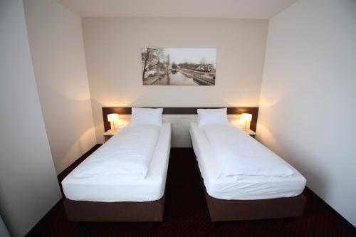 two beds in a small room with two lamps at Wellness penzion U GIGANTU in Plzeň