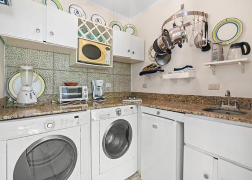 a kitchen with white cabinets and a washer and dryer at Bahia Pez Vela Resort in Ocotal