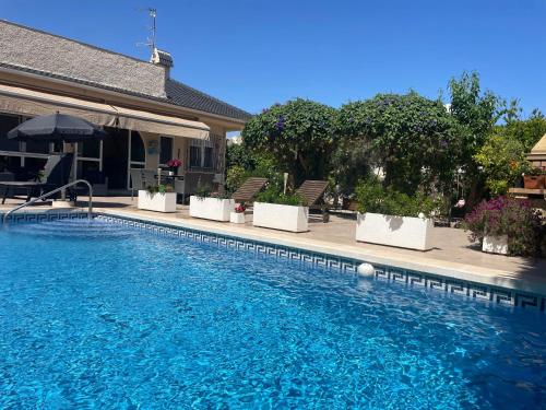 a swimming pool with blue water in front of a house at PARADISE GARDEN in Los Alcázares