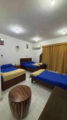 a room with three beds and a table in it at Sina house in Dahab