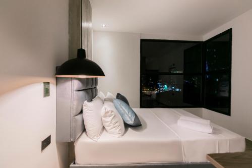 a bedroom with a bed with a lamp and a window at Apartahotel con Piscina in Medellín