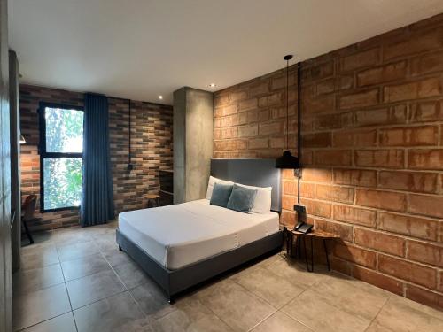 a bedroom with a bed and a brick wall at Apartahotel con Piscina in Medellín