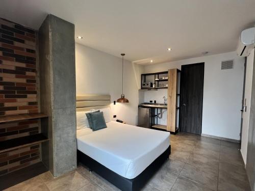 a bedroom with a white bed and a brick wall at Apartahotel con Piscina in Medellín