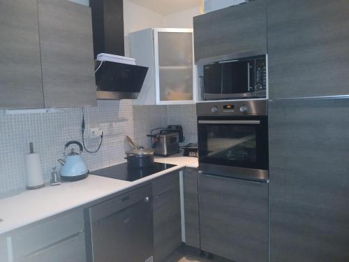 une cuisine avec des appareils en acier inoxydable et un micro-ondes dans l'établissement Maison familiale en Normandie, à Breteuil-sur-Iton