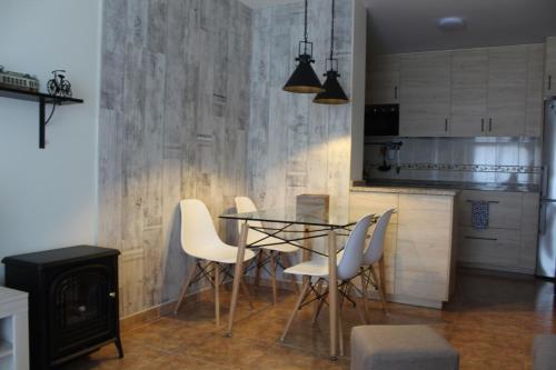 a dining room with a glass table and white chairs at Precioso apartamento en Boiro, Puerto de Escarabote in Magdalena