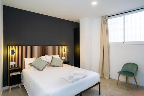 a bedroom with a large white bed and a chair at Nomad Malaga - Airport III in Málaga