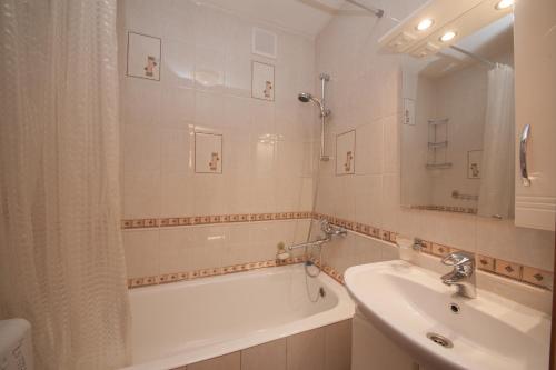 a white bathroom with a tub and a sink at Apartment na Vodopyanogo in Krasnoyarsk