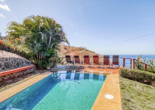 a swimming pool with chairs and the ocean in the background at Bahia Pez Vela Resort in Ocotal