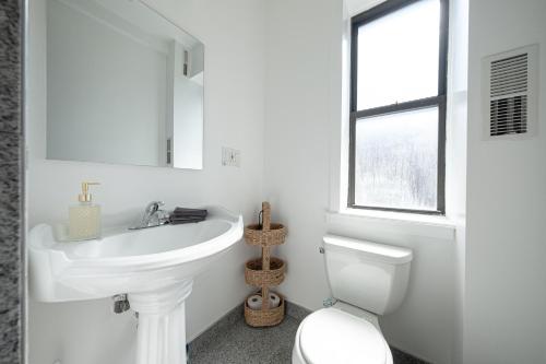 a white bathroom with a sink and a toilet at 3 Bedroom Home In Manhattan in New York