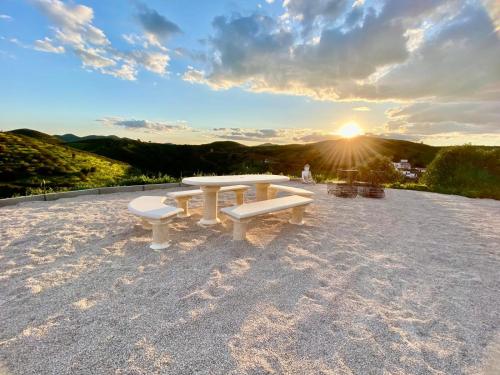 a table and benches on a roof with the sunset at Portugals Infinity Eco Suite Resort in Tavira