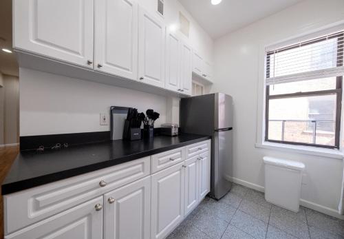 a kitchen with white cabinets and a refrigerator at 3 Bedroom Home In Manhattan in New York